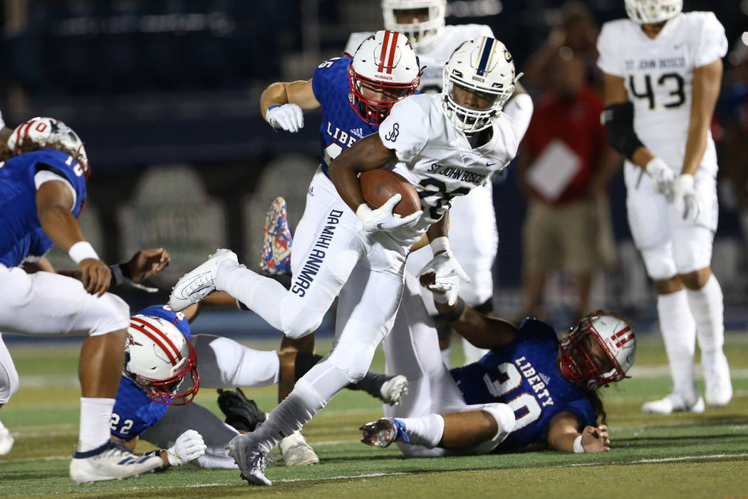 St. John Bosco's Michael Hayes (28) runs the ball against Liberty's Jayden Rookhuyzen (45), Tre ...