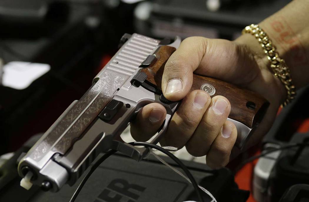 In this Jan. 9, 2016, file photo, a customer looks at a SIG Sauer hand gun at a gun show held b ...