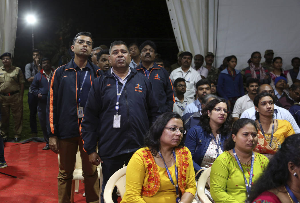 Indian Space Research Organization (ISRO) employees react as they listen to an announcement by ...