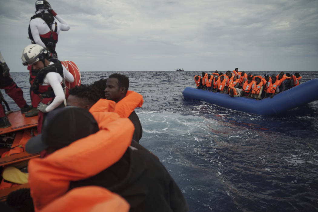 Migrants on a blue rubber boat wait to be rescued some 14 nautical miles from the coast of Liby ...