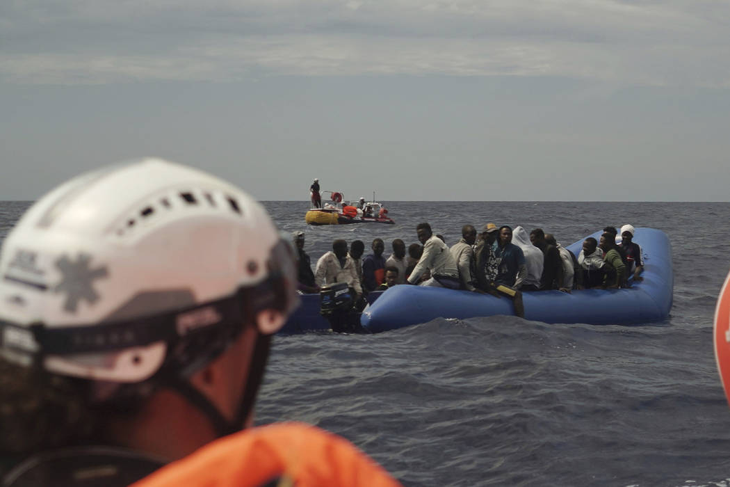 Migrants aboard an unseaworthy rubber boat wait to be rescued some 14 nautical miles from the c ...