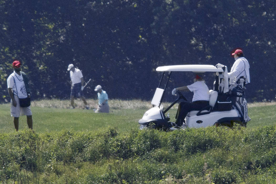 President Donald Trump, right, drives a golf cart during a round of golf at the Trump National ...