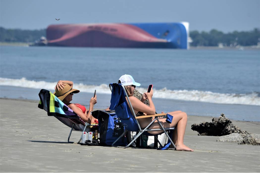 Rachel, left, and Sarah Mitchell look at their phones as they sun bathe on Jekyll Island's Drif ...