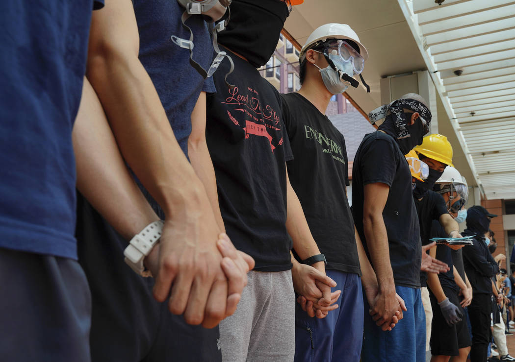 Students from Hong Kong University chains their hands outside schools in Hong Kong, Monday, Sep ...