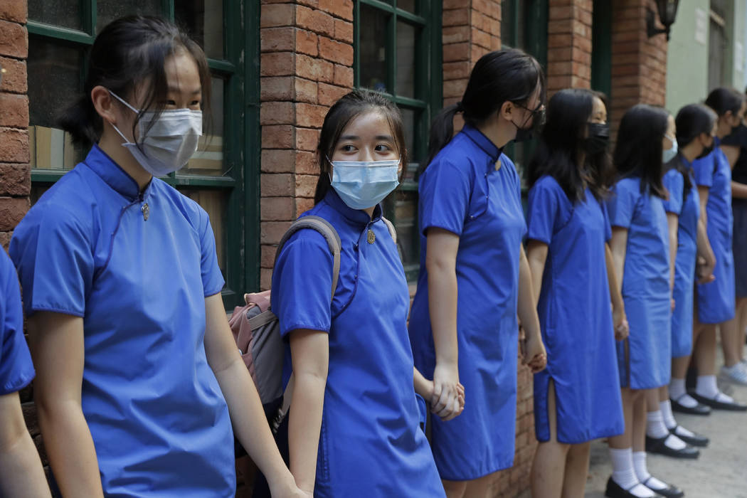 Students wearing mask hold hands to surround St. Stephen's Girls' College in Hong Kong, Monday, ...