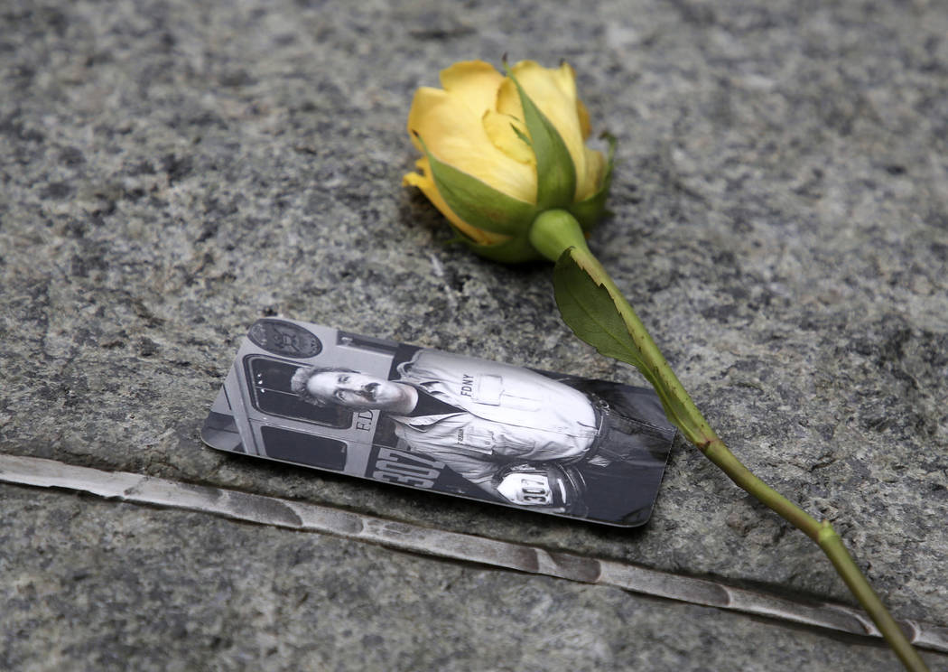 FILE - In this May 30, 2019 file photo, a rose rests next to a photograph of New York City Fire ...