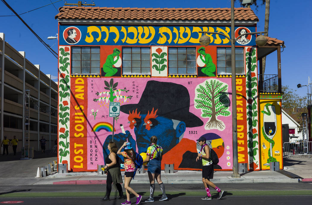 Attendees pass by a new mural during the first day of the Life is Beautiful festival in downtow ...