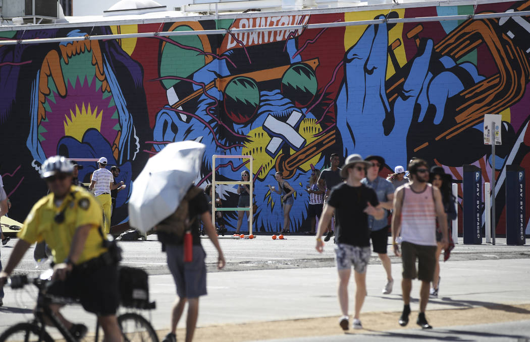 Attendees pass by a new mural during the first day of the Life is Beautiful festival in downtow ...