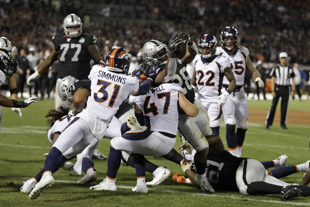 Oakland Raiders running back Josh Jacobs runs with the ball as Denver Broncos defensive end DeM ...