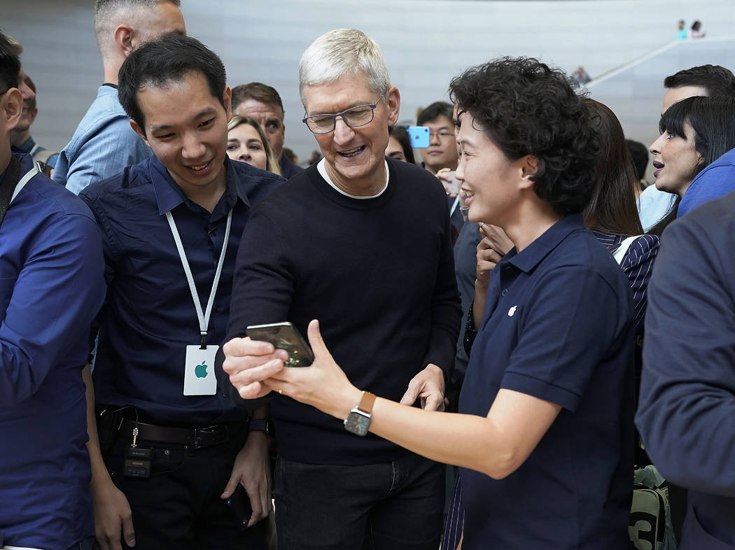 Apple CEO Tim Cook, center, looks at the the new iPhone 11 Pro Max, during an event to announce ...