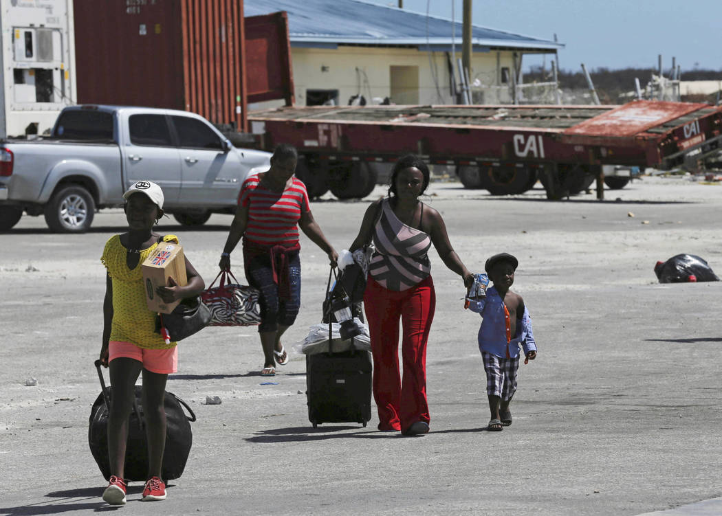 Evacuees carry their belongings as they walk to a ferry to depart for Nassau in the aftermath o ...