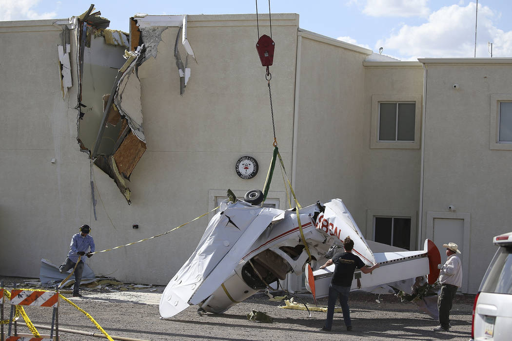 Workers set down a single-engine plane after it crashed into the terminal building shortly afte ...