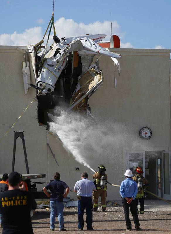 Fire personnel hose down the crash site as workers remove a single-engine plane after it crashe ...