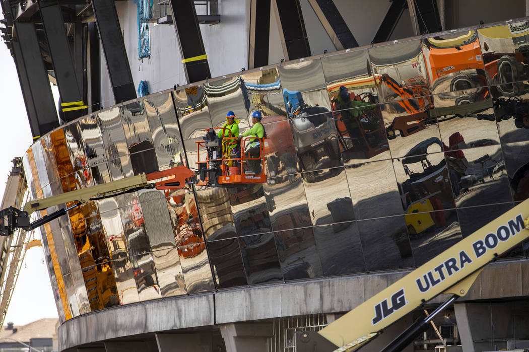 Crews work to install glass panes along the lower lever of Allegiant Stadium on Tuesday, Sept. ...