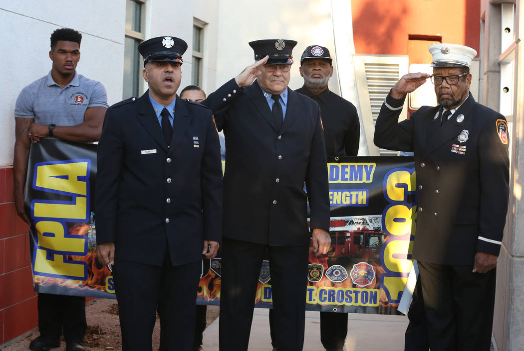 Frank Pizarro of Las Vegas, second left, a retired New York City firefighter, sings the Nationa ...