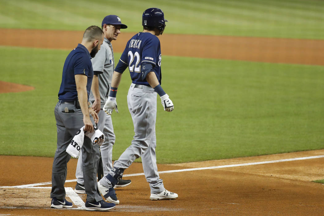 Milwaukee Brewers' Christian Yelich (22) walks off the field with a trainer and manager Craig C ...