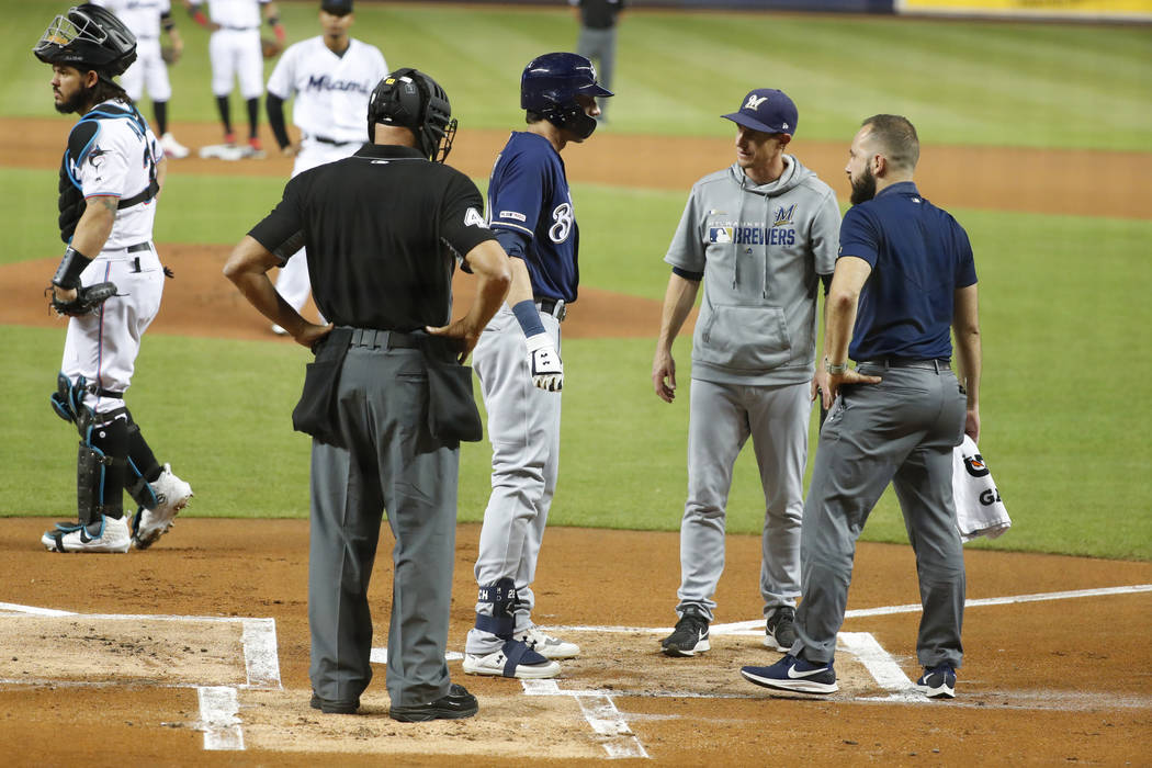 Milwaukee Brewers' Christian Yelich, second from left, is checked on by home plate umpire Kerwi ...