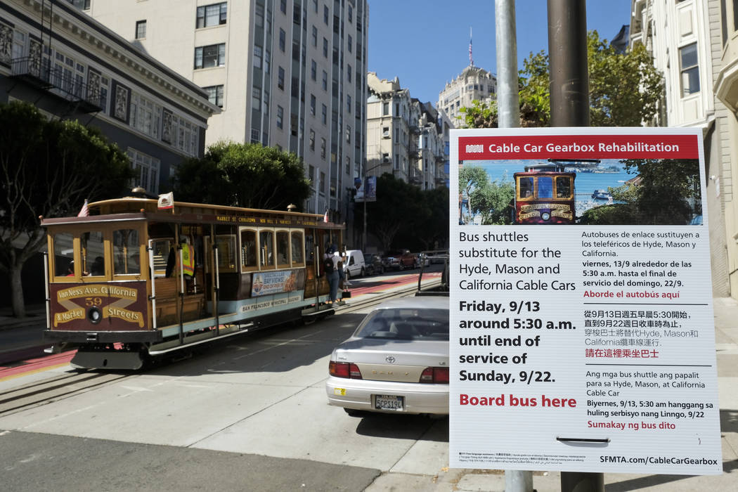 A cable car climbs California Street to Nob Hill past a sign announcing an upcoming rehabilitat ...