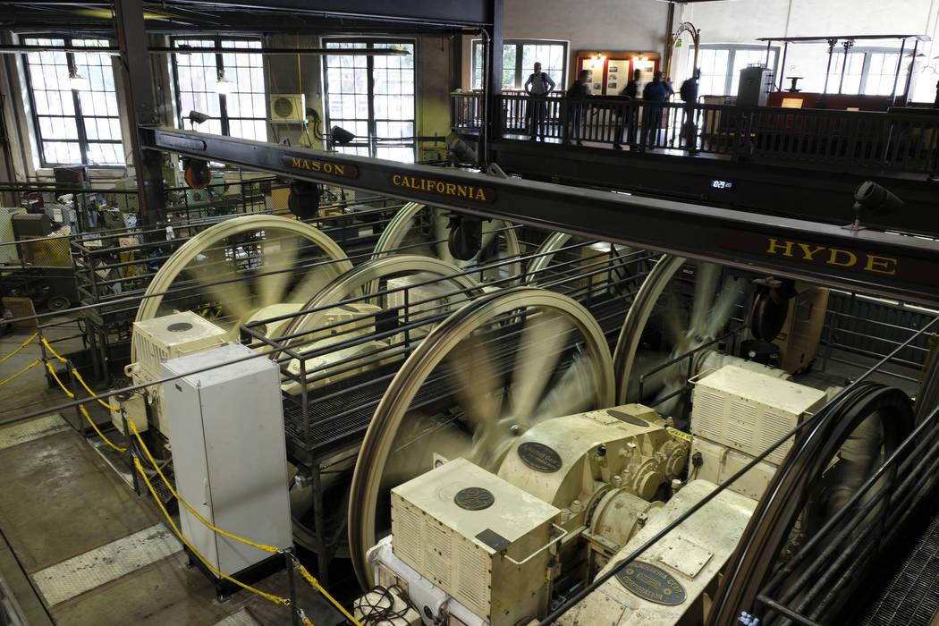 People stand above turning sheaves and gearboxes inside the cable car powerhouse Wednesday, Sep ...