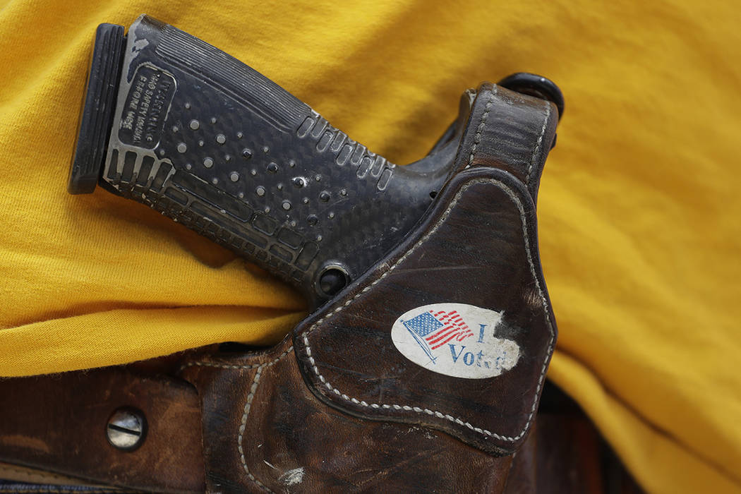 FILE - In this April 14, 2018 file photo, a man wears an unloaded pistol during a pro gun-right ...