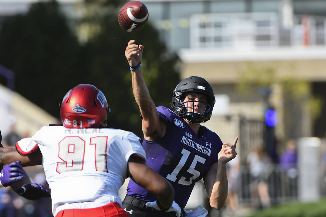 Northwestern quarterback Hunter Johnson (15) passes away from UNLV defensive lineman Nate Neal ...