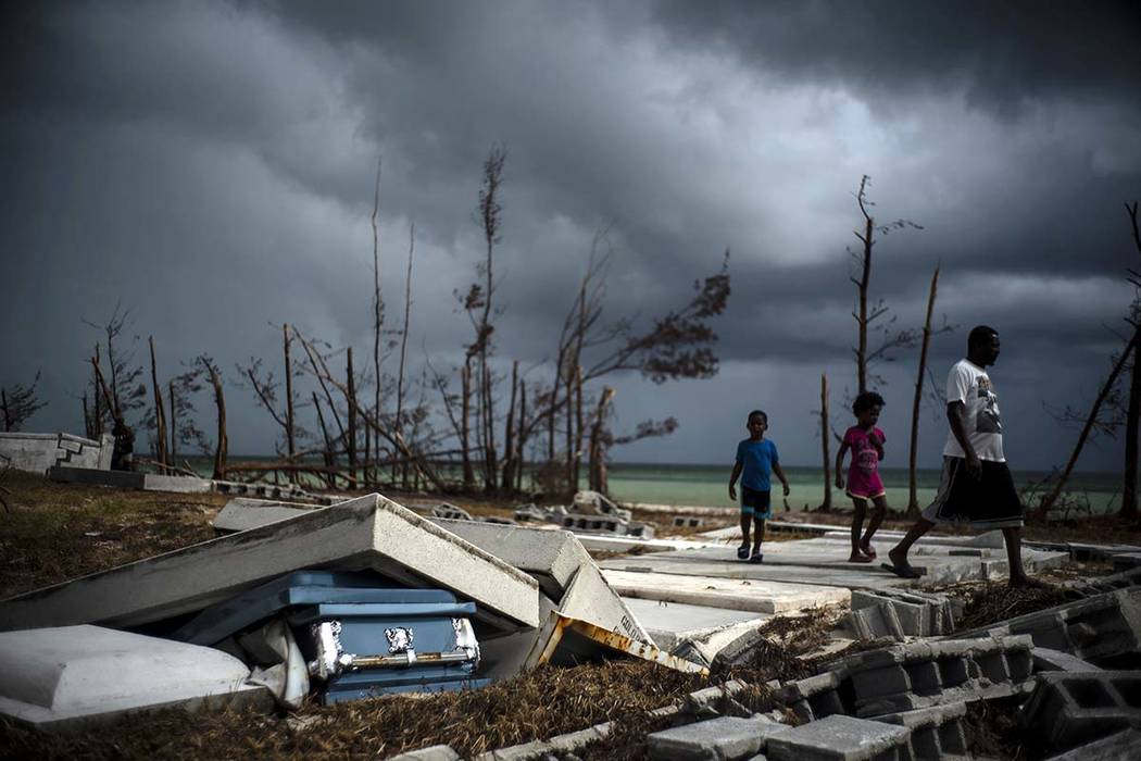 People walk next to a shattered and water-filled coffin lays exposed to the elements in the aft ...