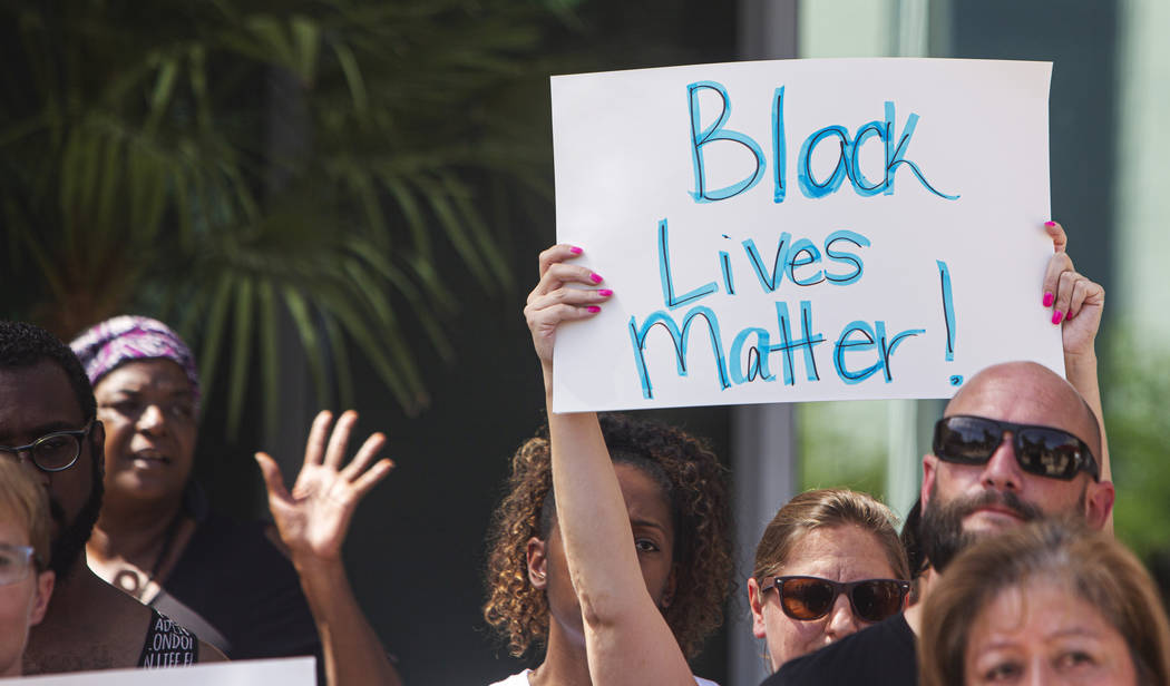 Attendees hold signs during a rally to protest the death of Byron Williams, the 50-year-old who ...