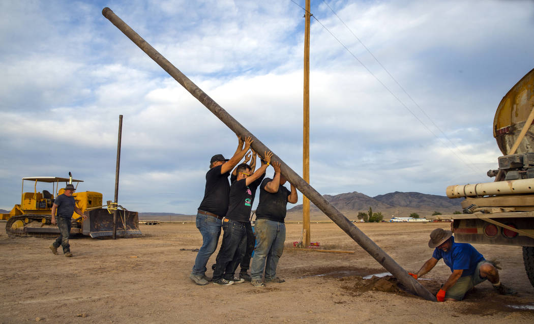 A crew works to set another pole for wireless internet service about the Alienstock festival gr ...