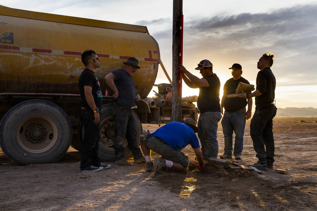 A crew works to set another pole for wireless internet service about the Alienstock festival gr ...