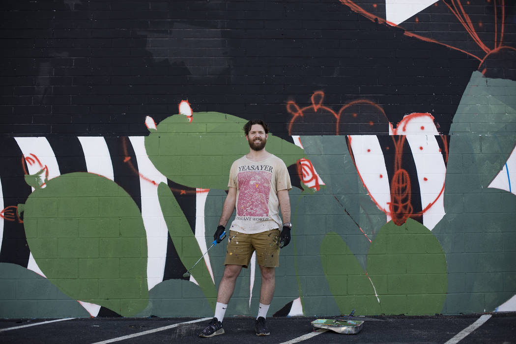 Artist Eric Vozzola stands in front of his mural-in-progress "An Allegory of Natural Beauty" fo ...
