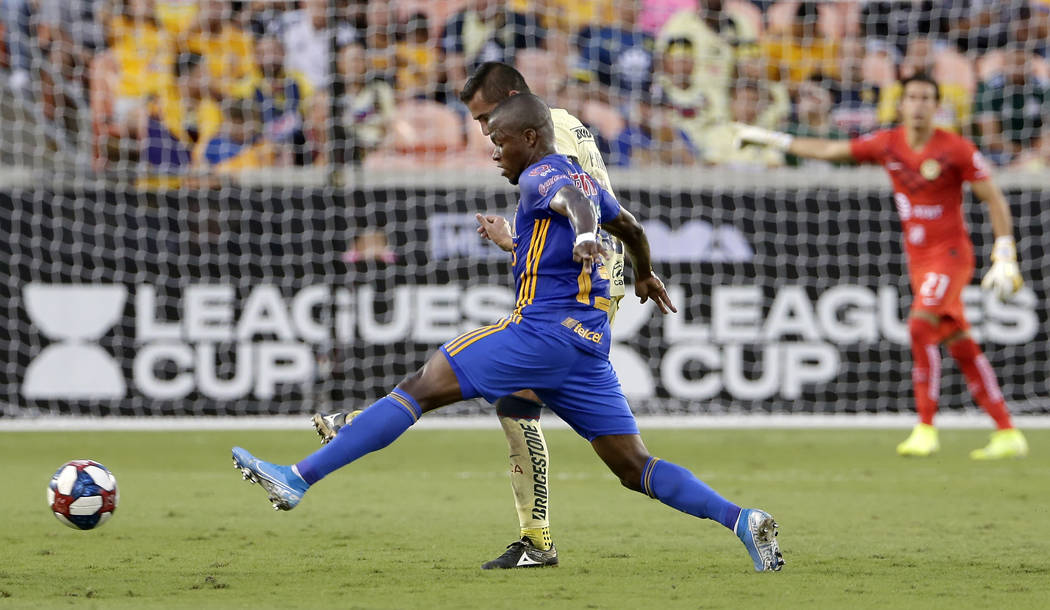 Tigres' Enner Valencia, front, moves the ball past Club America's Paul Aguilar, back, during th ...