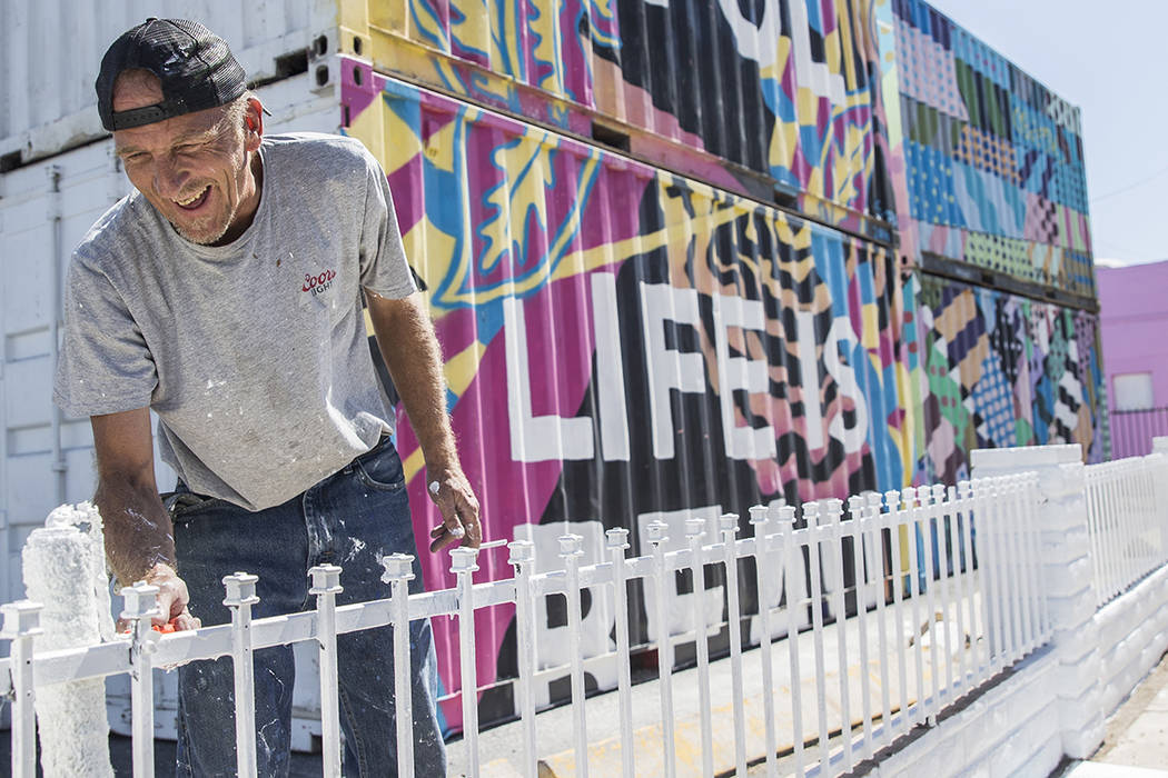 Jonathan Strublein paints a fence in preparation for Life is Beautiful music festival in downto ...