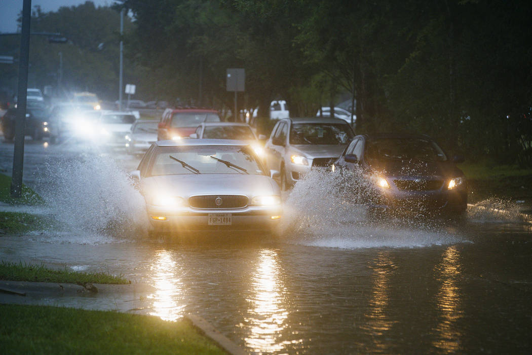 Vehicles splash through heavy water filling Chimney Rock, south of Brays Bayou in Houston, Tues ...