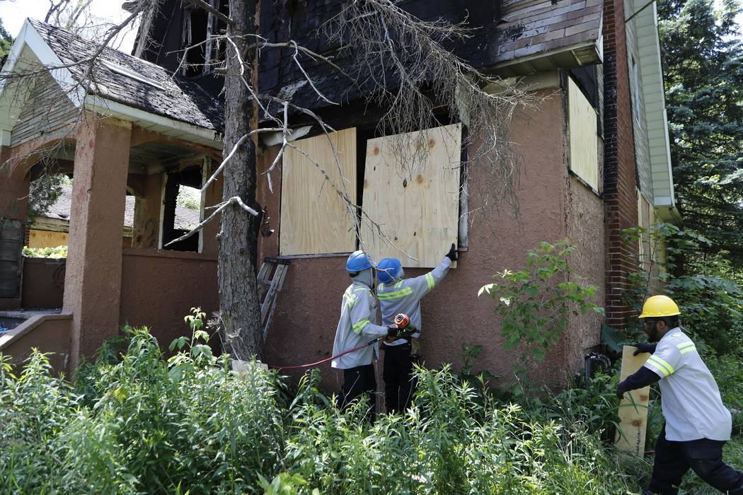 FILE - In this June 11, 2019 file photo, members of the Detroit's Board Up Brigade board up a v ...