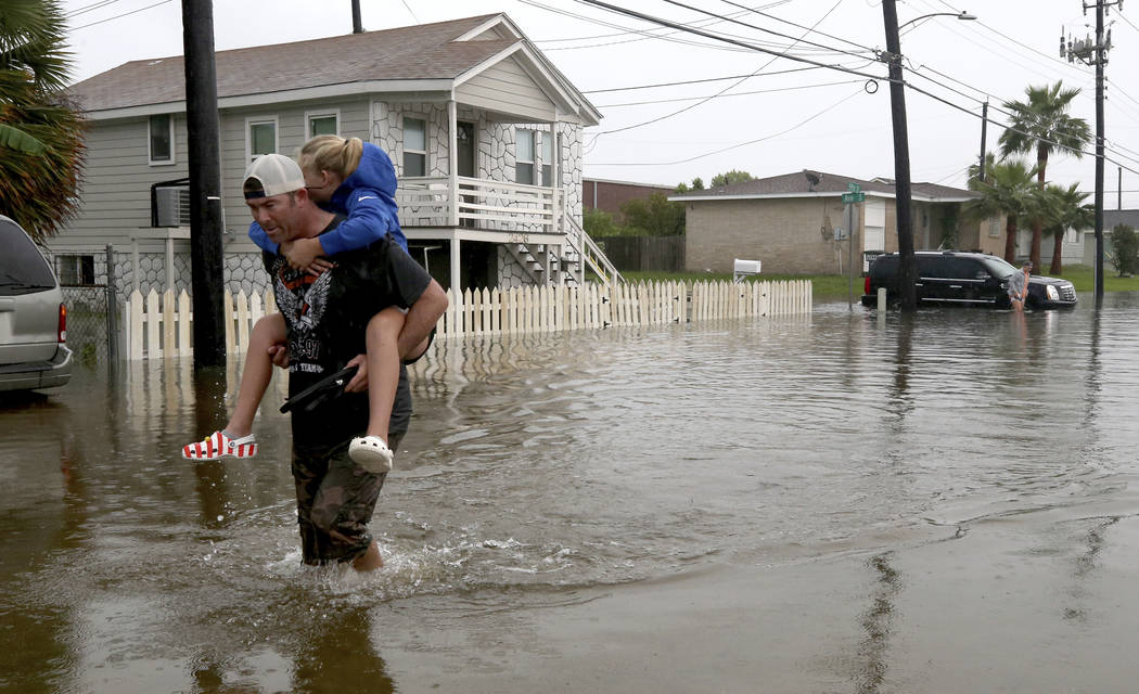 Terry Spencer carries his daughter, Trinity, through high water on 59th Street near Stewart Roa ...