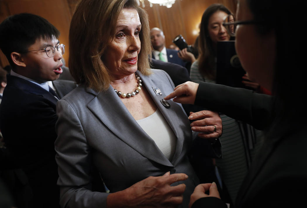 House Speaker Nancy Pelosi is given a lapel pin by a Hong Kong activist following a news confer ...