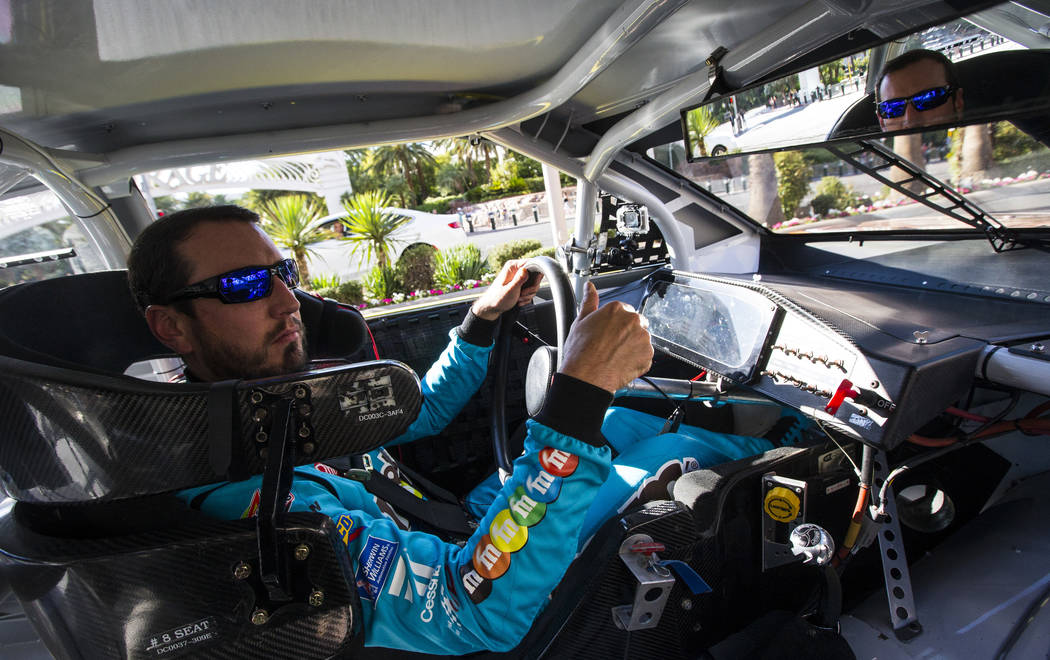 Kyle Busch motions to fans while passing The Mirage and The Venetian while driving down the Las ...