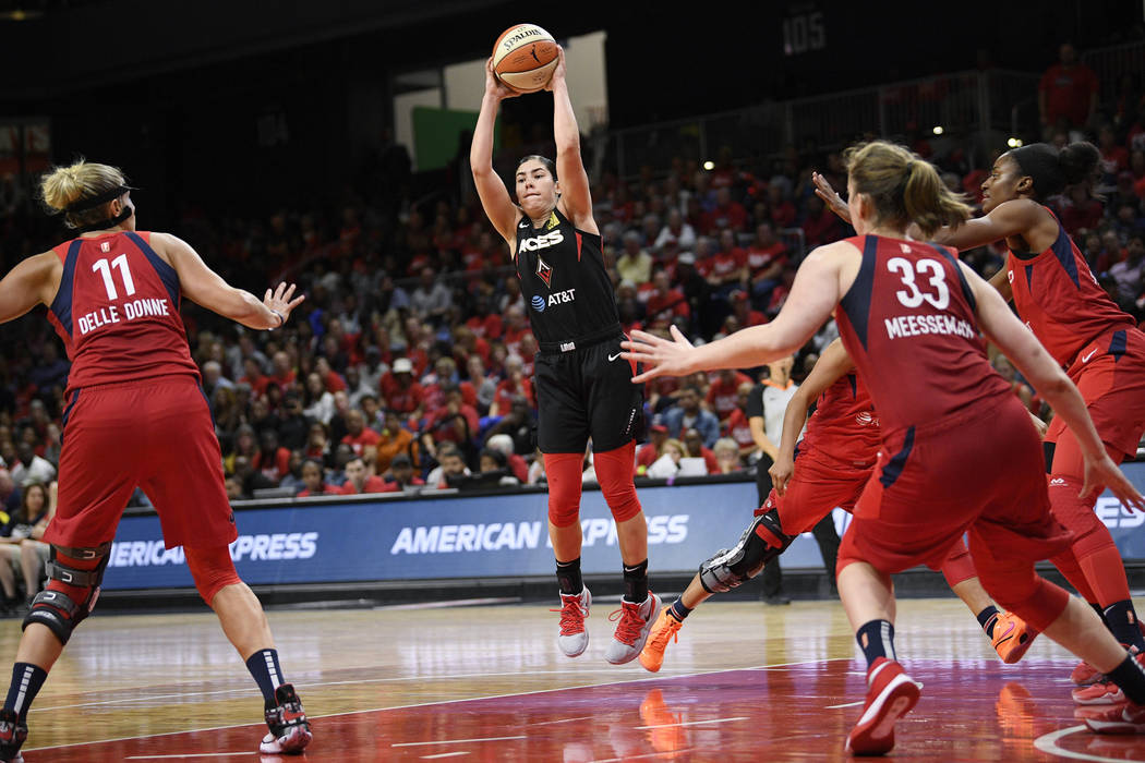 Las Vegas Aces guard Kelsey Plum, center, jumps up to pass the ball as Washington Mystics forwa ...