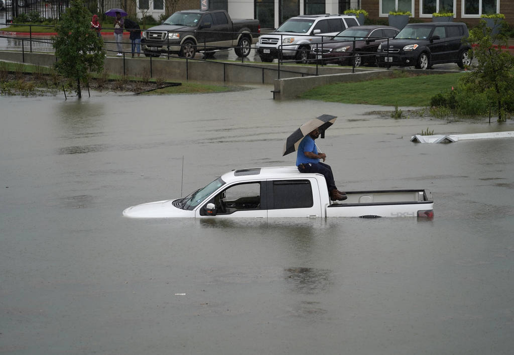 A man sits on top of a truck on a flooded road, Thursday, Sept. 19, 2019, in Houston. Members o ...