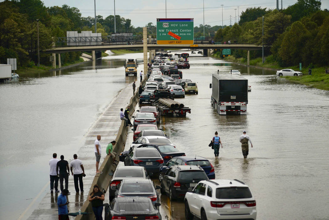 People wait outside of their stranded vehicles along Interstate 10 westbound at T.C Jester, Thu ...