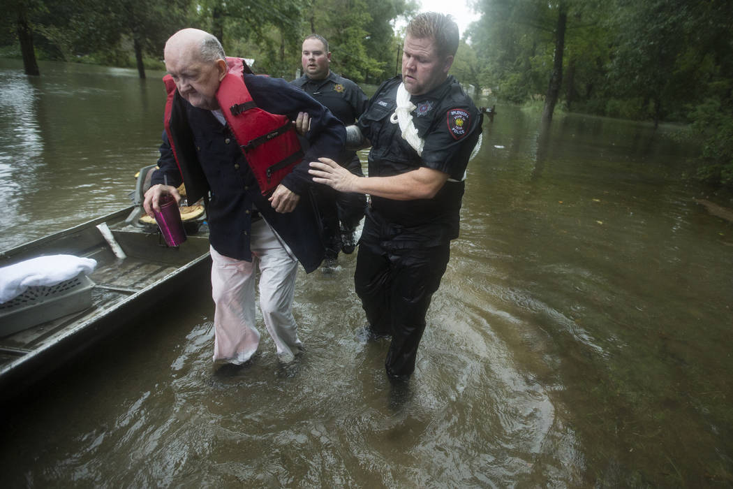 Fred Stewart, left, is helped to high ground by Splendora Police officer Mike Jones after he wa ...