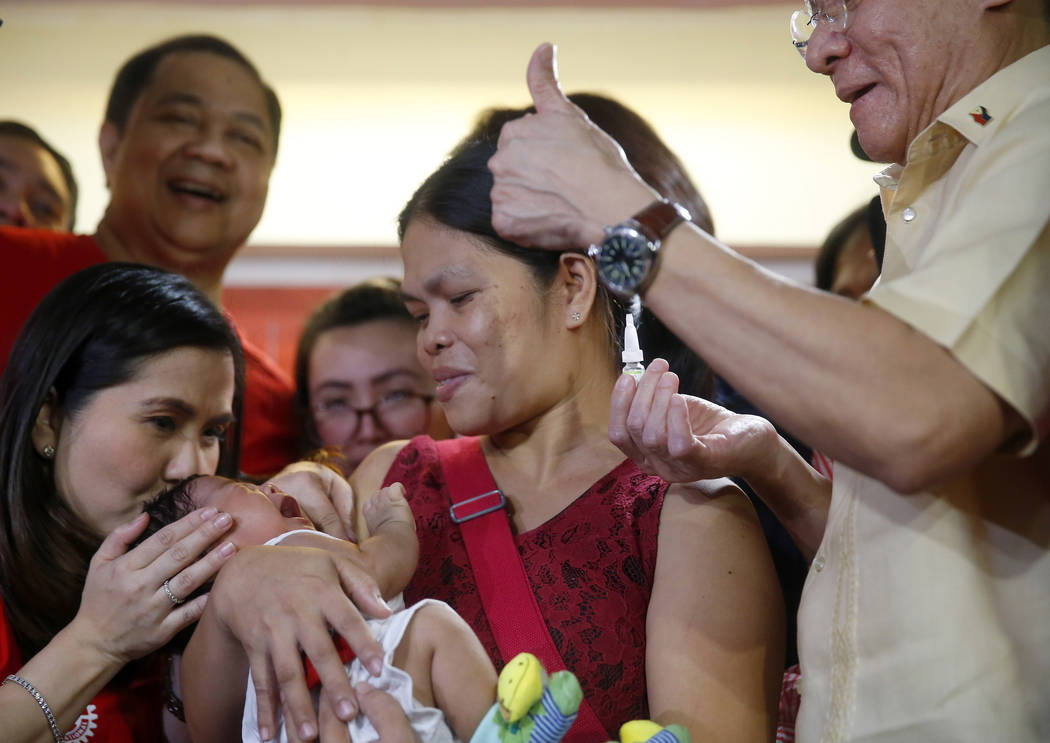 Philippine Health Secretary Francisco Duque III, right, flashes the thumbs up sign shortly afte ...