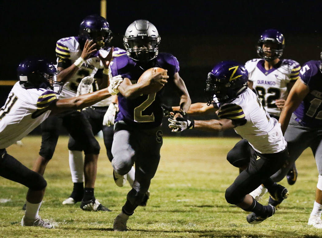 Silverado High's running back Aginae Cunningham (2) scrambles away from Durango High defense as ...