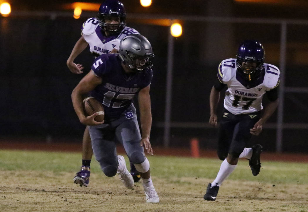 Silverado High's running back Jacob Mendez (12) runs past Durango High's Tyson Guild (82) and A ...