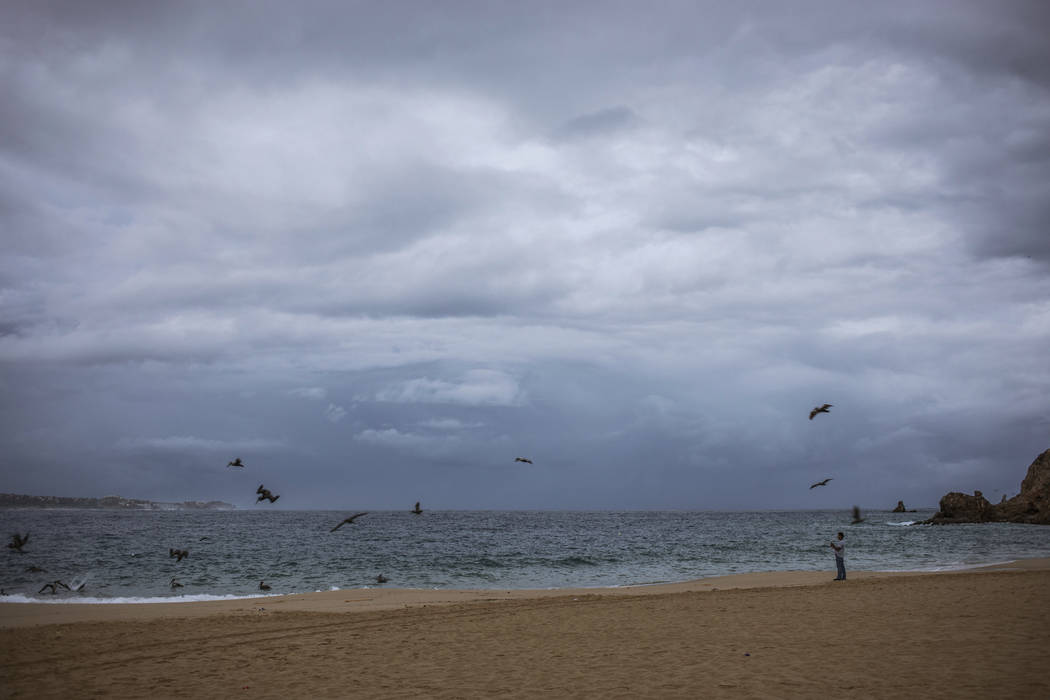 A tourist walks on the beach before the expected arrival of Hurricane Lorena, in Los Cabos, Mex ...