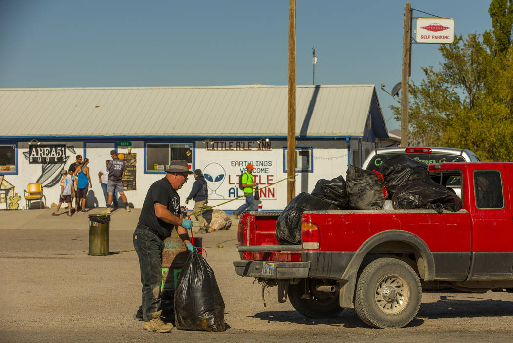 Kevin Dingo picks up bags of trash stacked in the parking area across from the Little A'Le'Inn ...