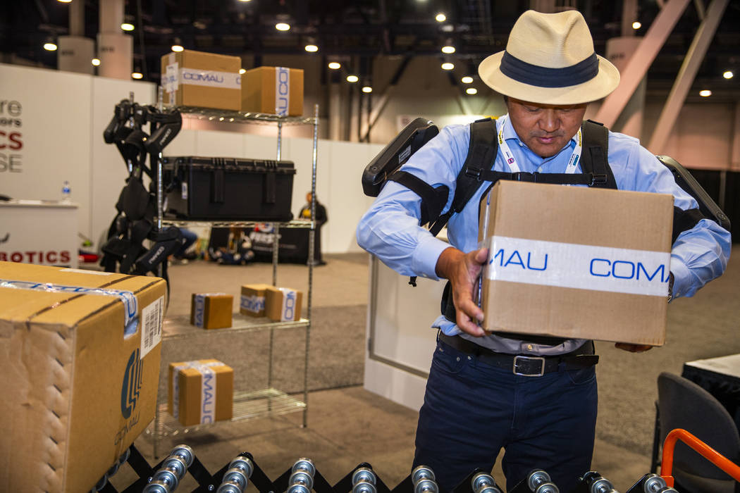 Attendee Toshiki Miyasaka lifts a box with the aid of a MATE Exoskeleton robotic apparatus at P ...