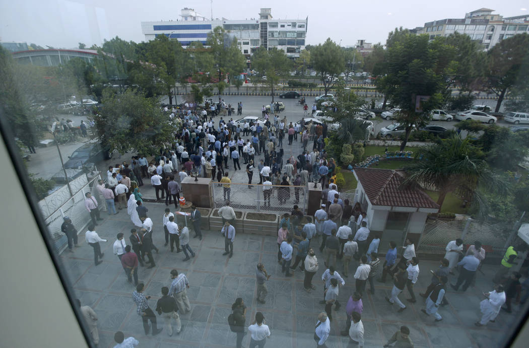 People stand outside their office after an earthquake is felt in Islamabad, Pakistan, Tuesday, ...