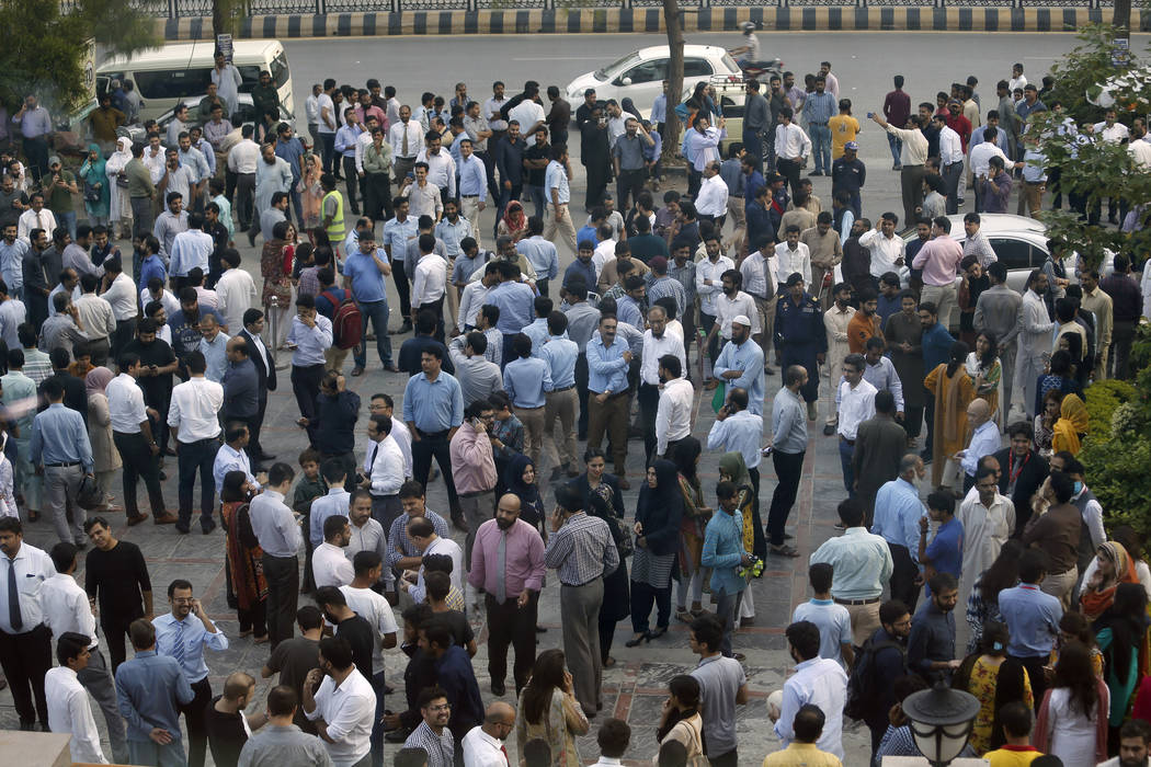 People stand outside their offices after an earthquake is felt in Islamabad, Pakistan, Tuesday, ...