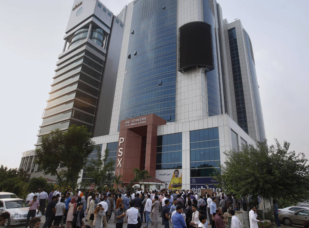 People gather outside their office building after an earthquake is felt in Islamabad, Pakistan, ...